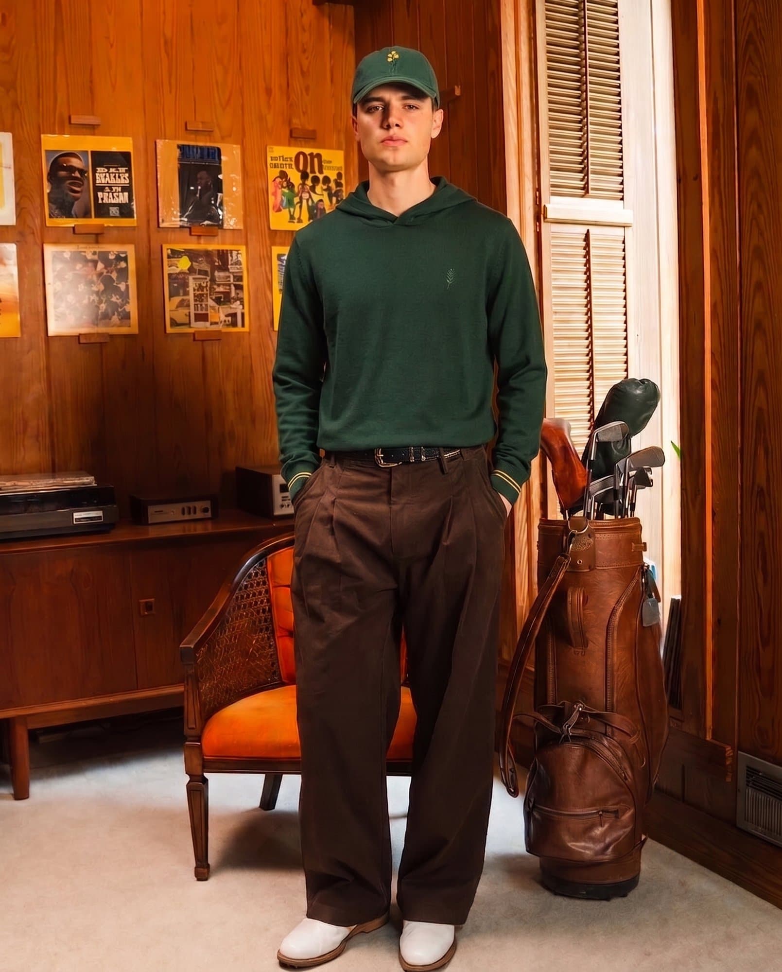 The knit hoodie worn with The Dad Cap in a wood-panelled clubhouse, a leather golf bag behind.