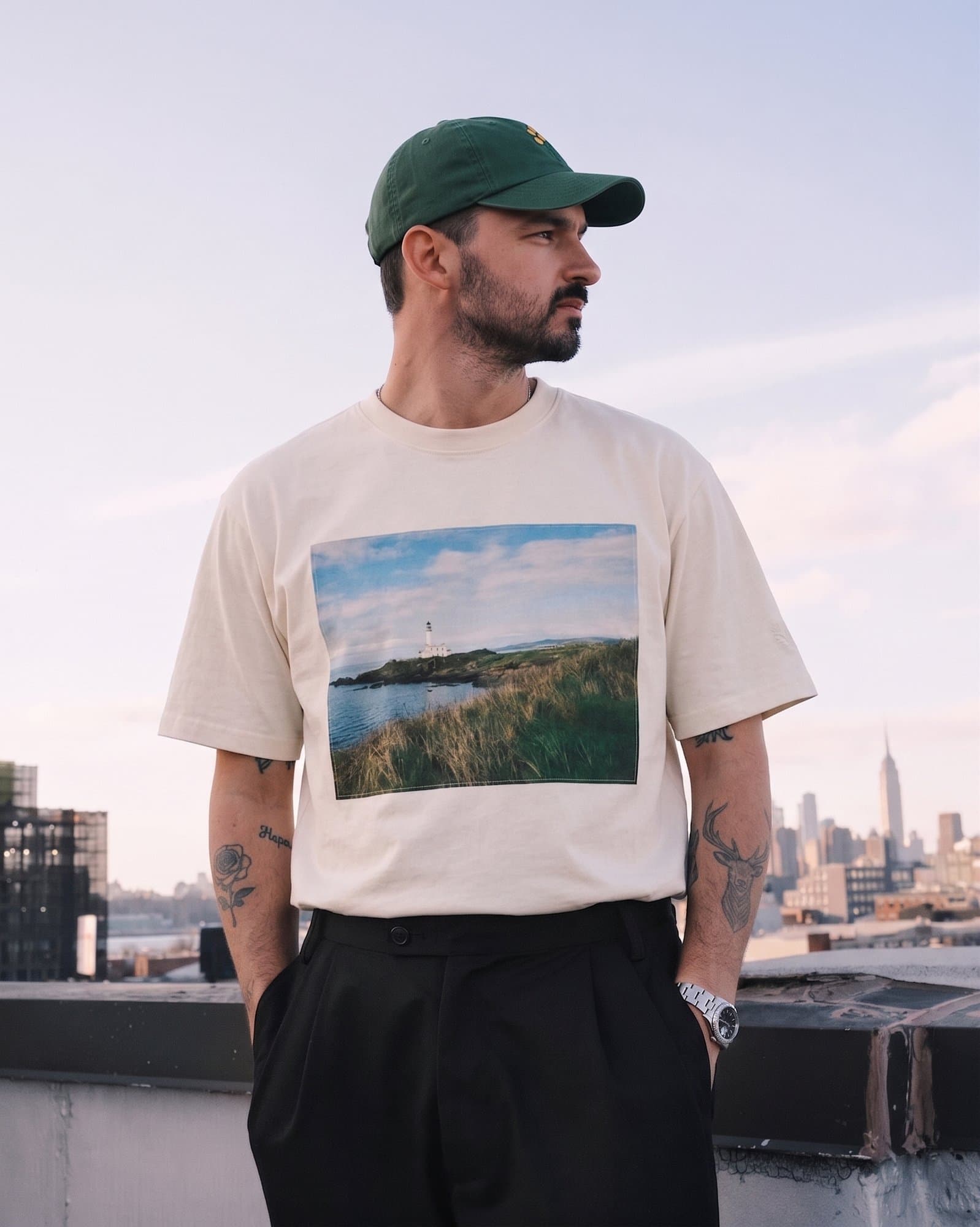 The photo tee and green Dad Cap worn against a city skyline.